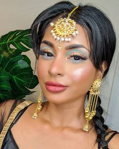 a woman with makeup on her face wearing gold jewelry and pearls, posing for the camera