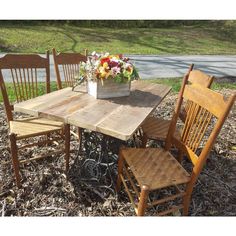 a wooden table with chairs around it and a bucket full of flowers on the table