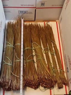 several bundles of straw sitting on top of a cardboard box next to a measuring tape