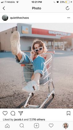 a woman sitting in a shopping cart with her feet up and sunglasses on, while talking on the phone