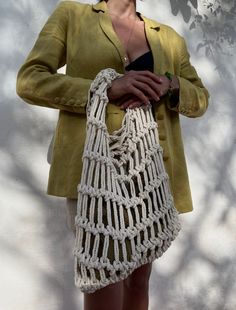 a woman holding a white crocheted purse