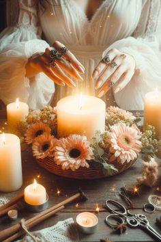 a woman is sitting in front of some flowers and candles with scissors on the table