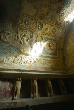 the ceiling is covered in intricate carvings and plasters, with sunlight shining through the window