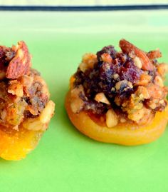 two small pastries with toppings on them sitting on a green surface, ready to be eaten