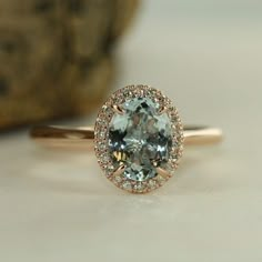 an oval shaped blue and white diamond ring on top of a table with a rock in the background