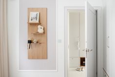 an open door leading to a white room with a wooden shelf on the wall next to it