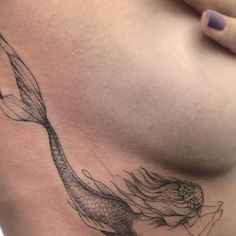 a woman's stomach with a tattoo of a mermaid on the side and her tail