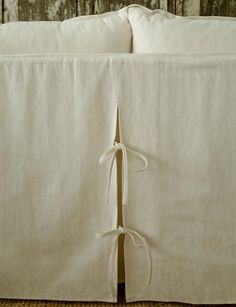 the back of a bed with white linens and ties tied up on each side