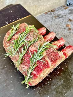 raw meat with rosemary on top sitting on a cutting board