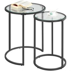 two tables with glass tops and metal legs, one has a book on top of it