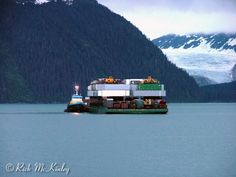 a large boat floating on top of a lake next to a mountain covered in snow