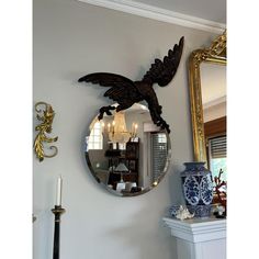 a mirror hanging on the wall next to a table with a vase and candle holder