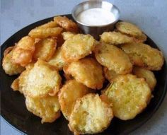 some fried food on a black plate with a small bowl of ranch dressing next to it