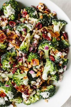 a white bowl filled with broccoli and cranberries on top of a table