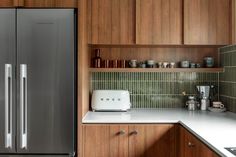 a kitchen with wooden cabinets and stainless steel refrigerator freezer combo in the center, along with white counter tops