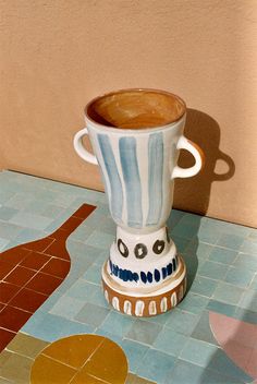 a coffee cup sitting on top of a blue and white tile floor next to a wall