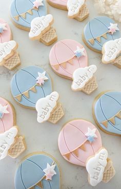 baby shower cookies decorated with blue, pink and white icing on a marble surface