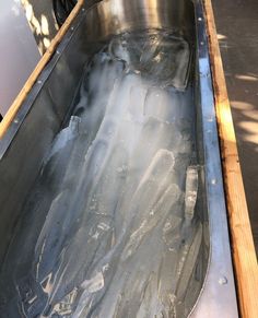 an empty metal container filled with ice on top of a wooden table