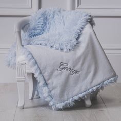 a white chair with a blue blanket on it and the word george written in cursive writing