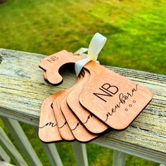 four wooden luggage tags with names on them sitting on a bench in front of some grass