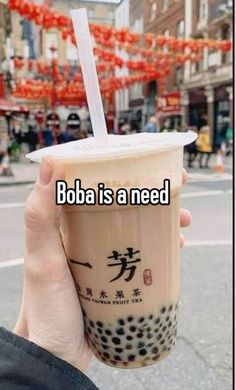 someone holding up a coffee cup with the words boba is a need on it