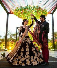 a man and woman standing next to each other in front of a colorful structure with flowers on it