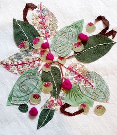 a close up of a flower made out of fabric and leaves on a table cloth