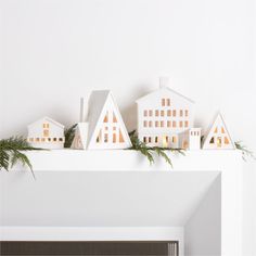 a fireplace mantel decorated with white houses and greenery