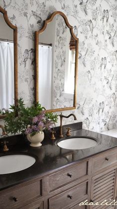 a bathroom with two sinks, mirrors and wallpapered walls in black and white