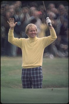 a man in yellow shirt and plaid pants holding up his golf club with both hands