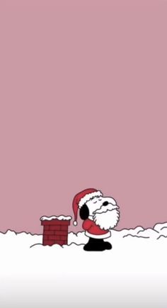 santa claus in the snow with a red brick wall and pink sky behind him,