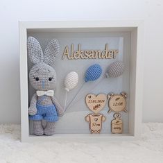 a crocheted stuffed animal is in a shadow box with the name alekssander on it