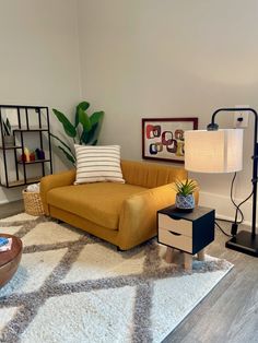 a yellow couch sitting on top of a rug in a living room next to a lamp