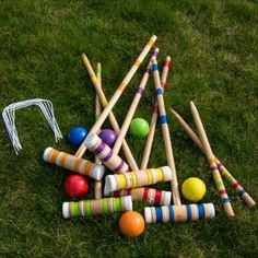 an assortment of wooden croquets and balls on the grass