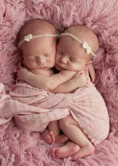 two newborn babies are sleeping together on a pink blanket with their arms around each other