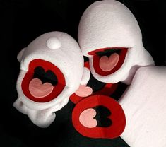 two stuffed animals with red and white faces on black surface next to each other, one has its mouth open