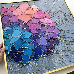 a person holding up a piece of stained glass with flowers on the inside and outside