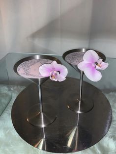 two silver trays with pink flowers on them sitting on a white furnishing