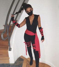 a woman dressed in black and red is standing on the stairs with her hands up