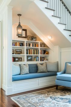 a blue couch sitting under a book shelf next to a stair case