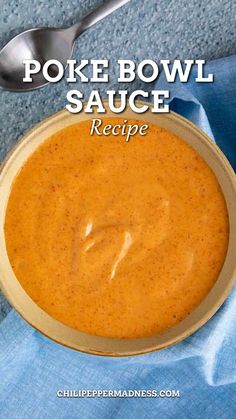 a bowl filled with sauce on top of a blue cloth next to a silver spoon