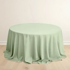 a round table with a light green cloth on it and wood floors in the background