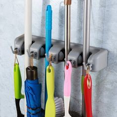 several umbrellas and cleaning brushes hanging on a hook in a bathroom with marble walls