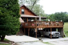 a car is parked in front of a house with a deck on the second floor