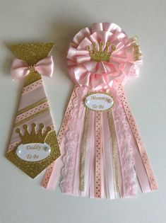 two pink and gold ribbons with a tiara on them, one is for a baby to be