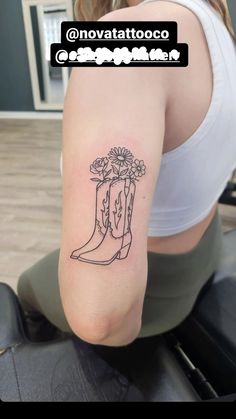 a woman's arm with a boot and flowers tattoo on the back of her shoulder