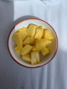 a bowl filled with cut up pineapples on top of a white table cloth