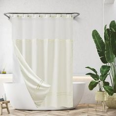 a white shower curtain in a bathroom next to a bathtub and potted plant