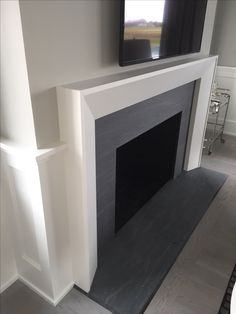 a flat screen tv mounted on the wall above a fireplace in a room with white walls