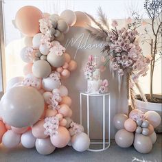 the balloon arch is decorated with pink and white balloons, flowers, and greenery